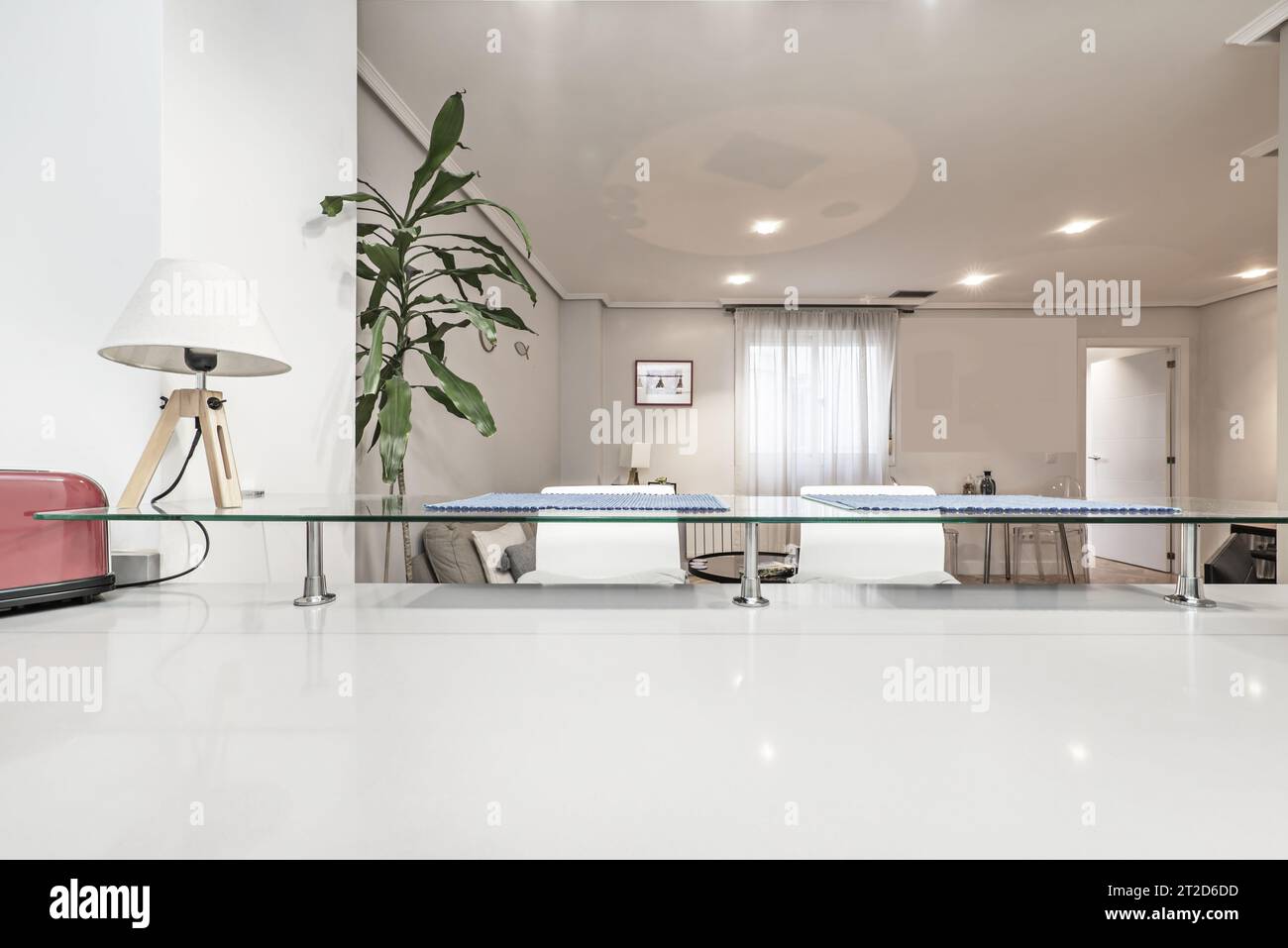 Offene Küchenzeile aus weißem Holz mit Zugang zu einem Wohnzimmer mit Fenstern Stockfoto