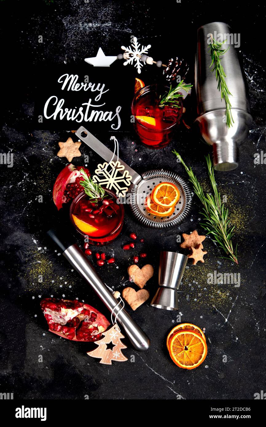 Winter-weihnachtscocktail mit Granatapfel und Rosmarin in einem Glas auf schwarzem Hintergrund. Draufsicht. Stockfoto