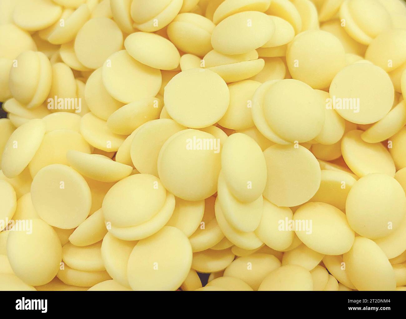 Weiße, süße, leckere Schokoladen zum Temperieren. Kleine runde Schokoladenstücke für Süßwaren. Stockfoto