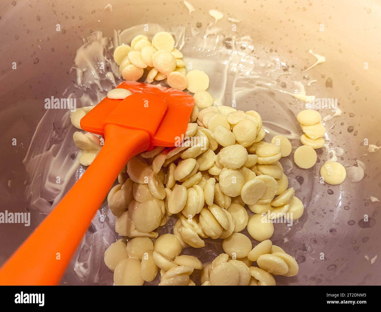 Geschmolzene heiße, weiße, leckere, süße, runde Schokoladenkolben aus belgischer Milchschokolade zum Temperieren und Zubereiten hausgemachter süßer Desserts und Garn Stockfoto