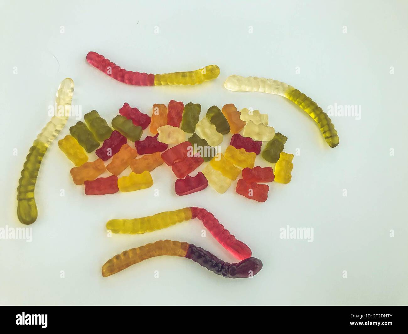Gummibonbons liegen auf weißem mattem Hintergrund. Gelatinöse Würmer und Bären unterschiedlicher Farben miteinander verwoben. Köstliche kulinarische MAS Stockfoto