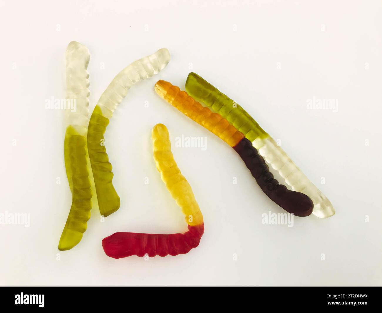 Gummiwürmer liegen auf weißem, mattem Hintergrund. Helle, mundtränende gelatinöse Würmer unterschiedlicher Farben. Köstliches und süßes Dessert. Köstliche Süßigkeiten Stockfoto