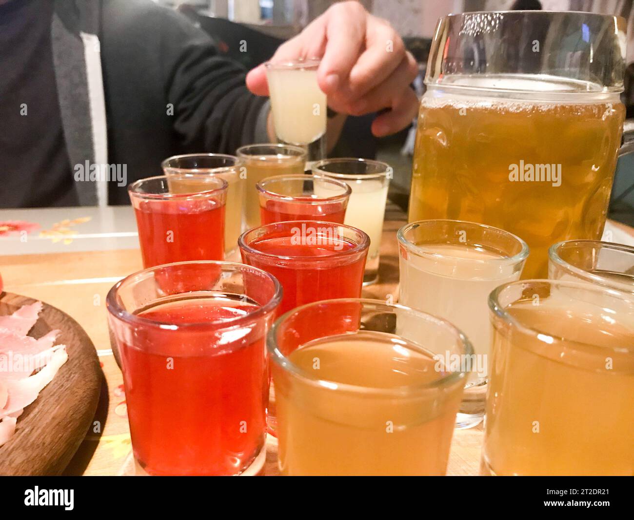 Eine Reihe von leckeren gelben orange roten Gläsern, Schüsse mit starkem Alkohol, Wodka, Brandy, Brandy, Bier auf Holzständern auf einem Tisch in einem Café, BA Stockfoto