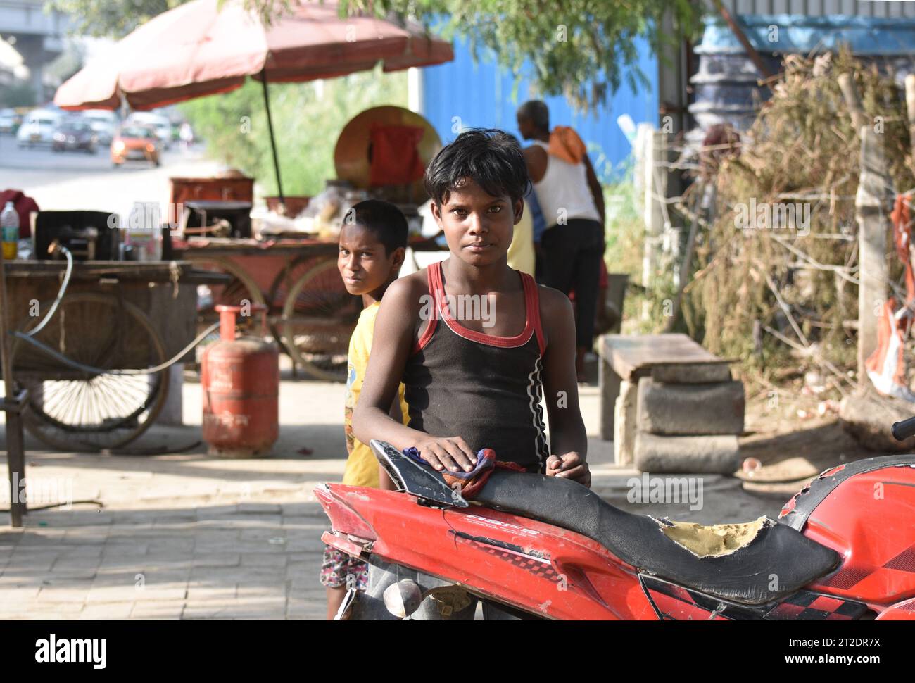 Ein Junge im Alter von etwa 12 Jahren, der den Sitz eines zurückgewonnenen Motorrads putzt, das er auf den Straßen von Neu-Delhi renovieren will Stockfoto