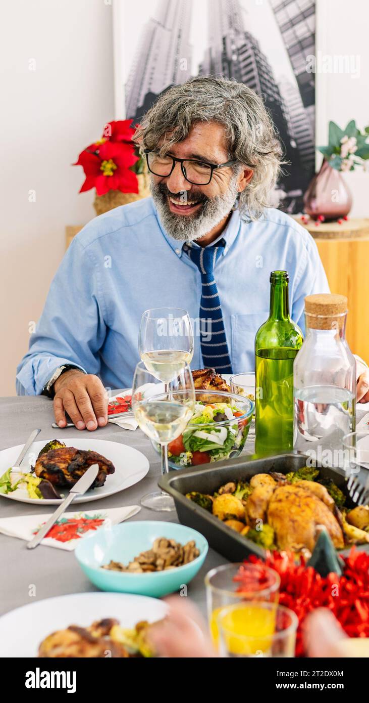 Ein älterer Erwachsener versammelte sich mit der Familie um den Tisch und feierte das weihnachtsessen Stockfoto