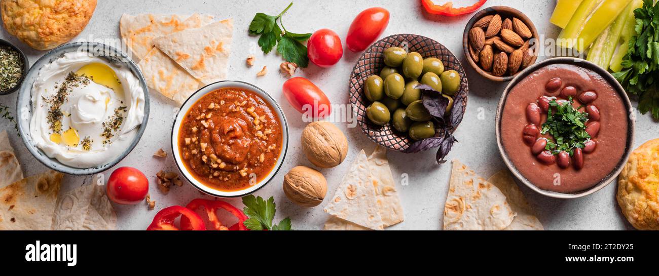 Auswahl an arabischen Mezze-Speisen - foul, Labneh-Joghurt, Muhamara-Dip auf weißem Hintergrund, Blick von oben, Banner. Nahöstliche Küche. Stockfoto