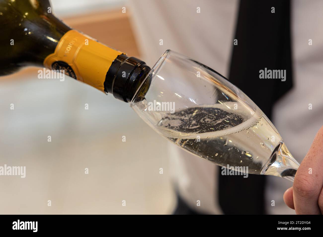 Ein Glas Champagner, das bei einer Party/einem gesellschaftlichen Ereignis gegossen wird Stockfoto