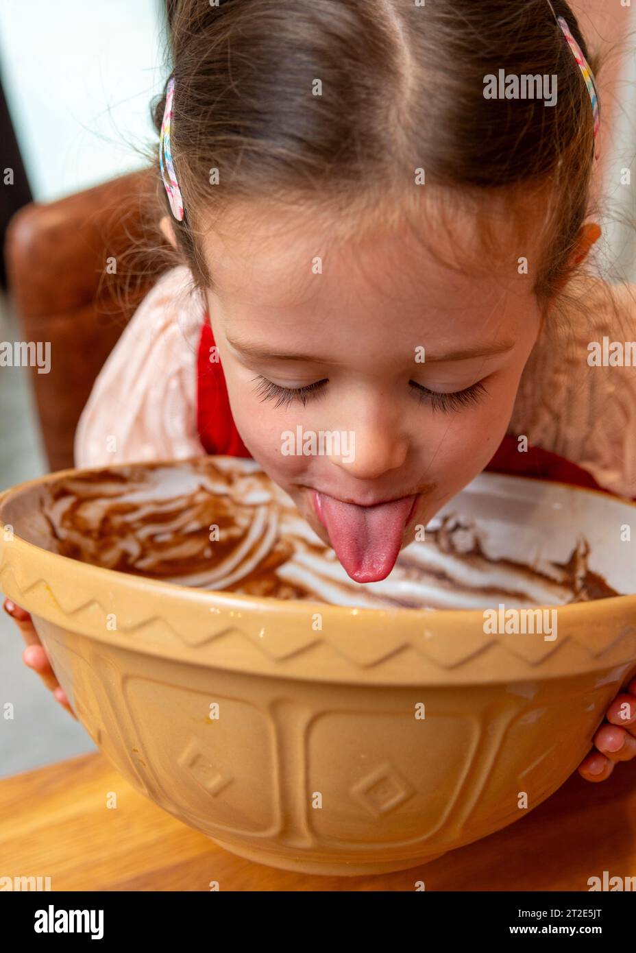 Kind leckt Kuchen aus einer Schüssel Stockfoto