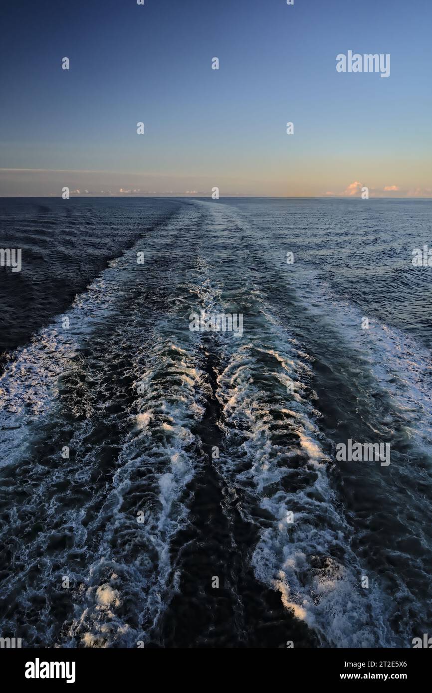 Rückansicht Kreuzfahrtschiff leer kalte Nordsee Norwegen mit Wake Water Trail. Geradlinige Wellenlinie und weißer Schaum vor Sonnenaufgang Urlaubskonzept Stockfoto