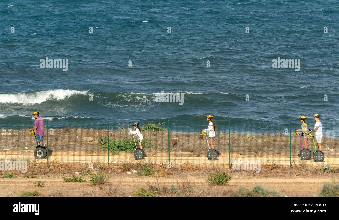Touristen auf Segways, die entlang des neuen Küstenweges zwischen Paphos Hafen und Paphos Stadtstrand fahren, Paphos, Zypern Stockfoto