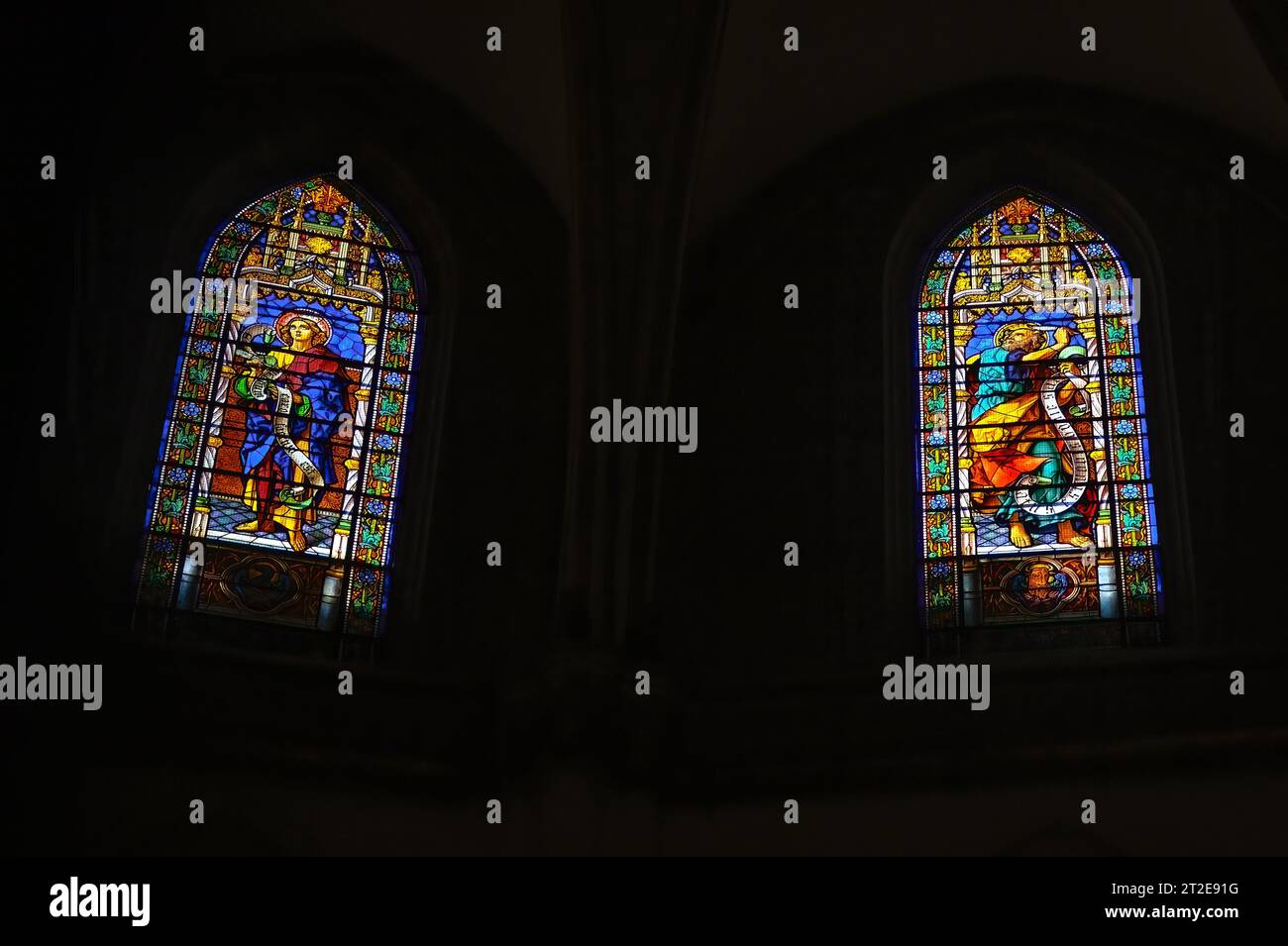 Murcia, Spanien, hintergrundbeleuchtete Szene von zwei Buntglasfenstern im Inneren der Kathedrale. Die Glaskunst hat religiöse katholische Symbole. Stockfoto