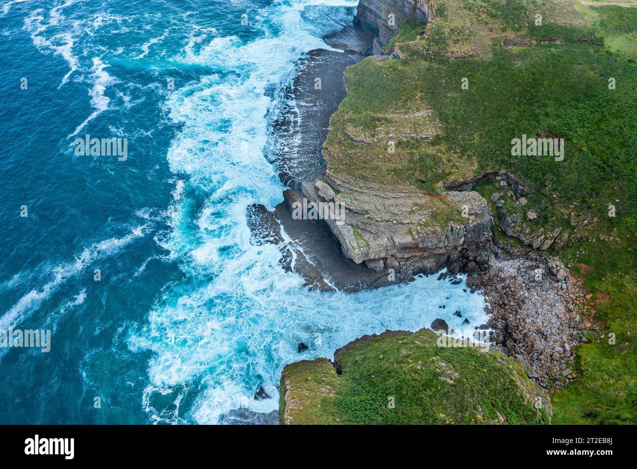 Aus der Vogelperspektive auf eine Küstenlandschaft mit felsigen Klippen und grünen Wiesen. Kantabrien, Spanien. Stockfoto