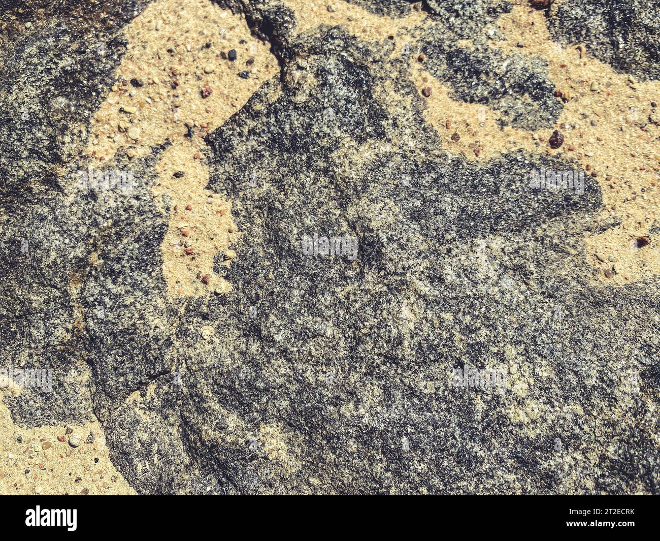 Natürliche Textur. Mehrfarbiger Stein. Grau-rosa Zeichnung auf Naturmaterial. Bergwelt. Sand auf Stein, natürliches Bild. Stockfoto