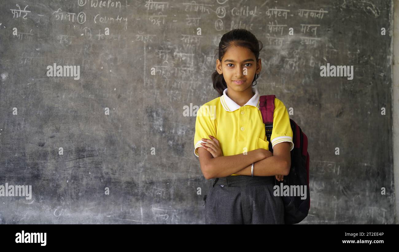 Glückliche indische Grundschüler, die am Schreibtisch im Klassenzimmer sitzen und in Notizbuch mit Bleistift schreiben, Prüfung und Test, weibliche Lehrerin Stockfoto