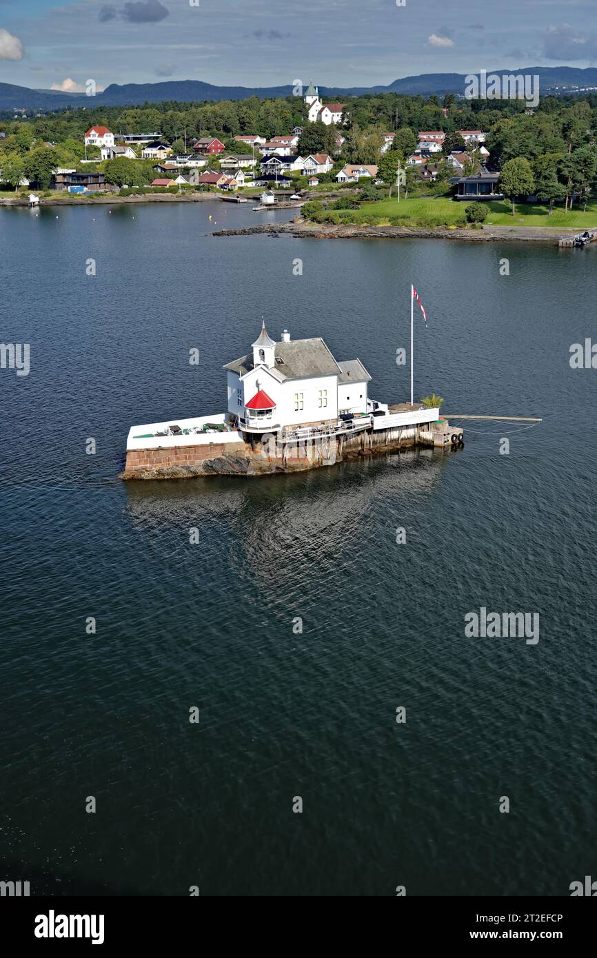 Blick auf den Dyna fyr Lighthouse, der auf einem felsigen Riff gebaut wurde, am Meer mit Häusern. Oslo Fjord in der Nähe des Hafens von Oslo, Norwegen Urlaubs- und Reisekonzept Stockfoto