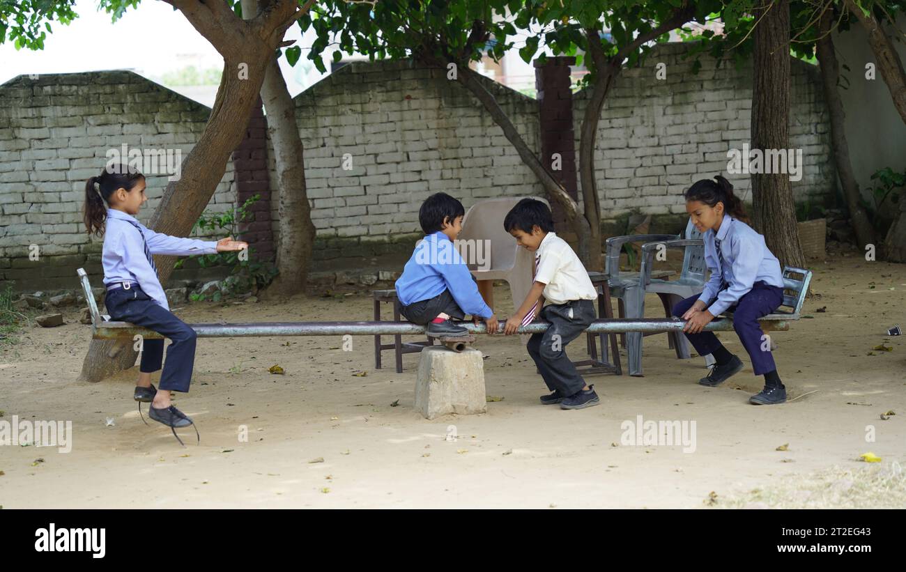 Kleine Kinder haben Spaß mit der Schaukel auf dem Spielplatz im Freien. Kinder, beste Freunde und Geschwister schaukeln an warmen sonnigen Frühlings- oder Herbsttagen. Aktives Leisu Stockfoto