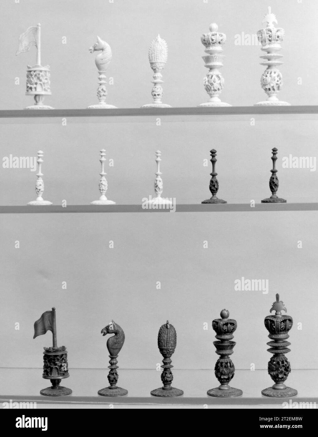 Chessmen (32) Chinesisch 19. Jahrhundert diese Chessmen mit Balusterstielen und Finialen, die den Rang des Stücks bezeichnen, basieren auf europäischen Vorbildern; das Werk ist jedoch unverkennbar orientalisch. Die Könige und Königinnen sind durch Kronen gekennzeichnet, die Bischöfe durch Miteren; die Ritter sind Pferdeköpfe und die Türme haben die Form von zinnenbesetzten Türmen mit großen Fahnen an der Spitze. Die Bauern sind schlank und elegant. Die Balusterständer sind alle mit einem geschnitzten, durchbohrten und unterschnittenen Knopf versehen, der im Turm die Masse des Turms bildet. Die Basen sind typisch für viele chinesische Sets. Stockfoto