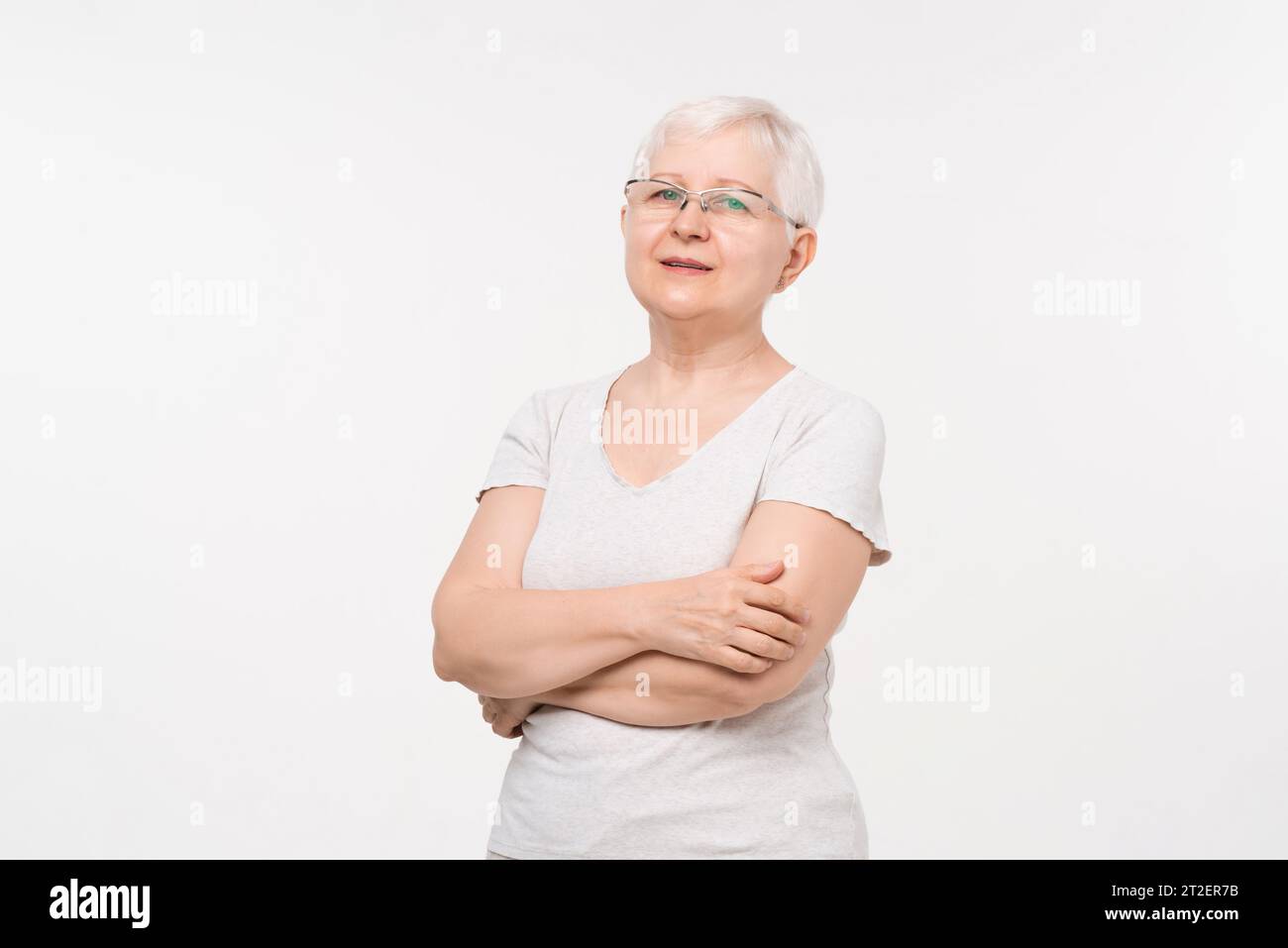 Gesundes weißes Haar ältere kaukasische Frau mit Armen gekreuzt Studio Porträt in weißem Hintergrund Stockfoto
