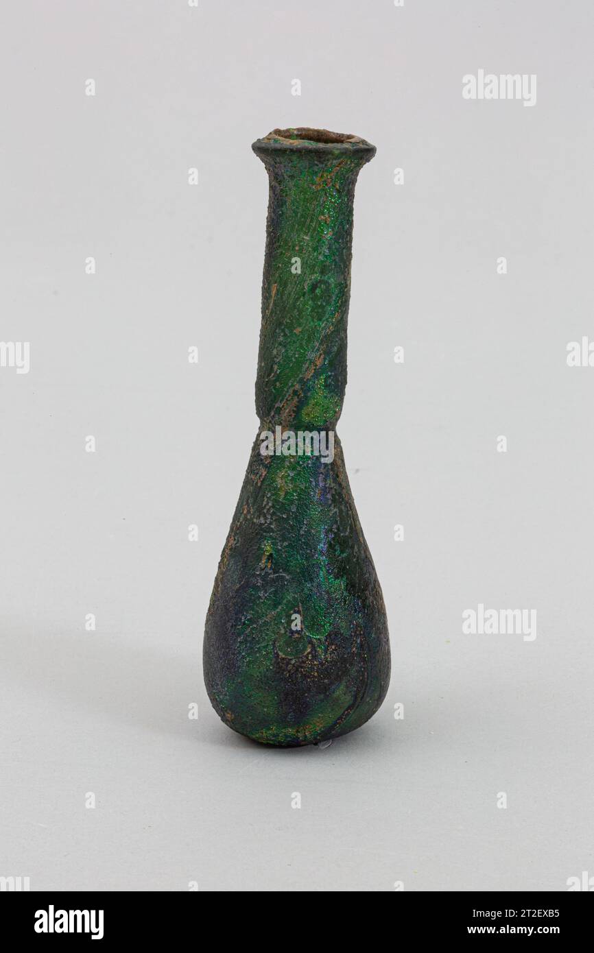 Glasparfümflasche Roman Ende 1.–2. Jahrhundert CE durchscheinend tiefes Smaragdgrün.umgestürzter Rand, umgefaltet, mit abgeschrägter äußerer Lippe; hoher zylindrischer Hals, mit angefertigter horizontaler Einbuchtung um die Basis; konischer Körper mit abgerundetem unteren Rand; Boden leicht eingedrückt.intakt; viele Nadelstichbläschen; tiefe Lochbildung, Verwitterung, und brillant schillernd. dickwandiges, schweres Gefäß. Mehr anzeigen. Parfümflasche aus Glas. Roman. Ende 1.–2. Jahrhundert n. Chr. Glas; geblasen. Von Anfang bis Mitte Imperial. Glas Stockfoto