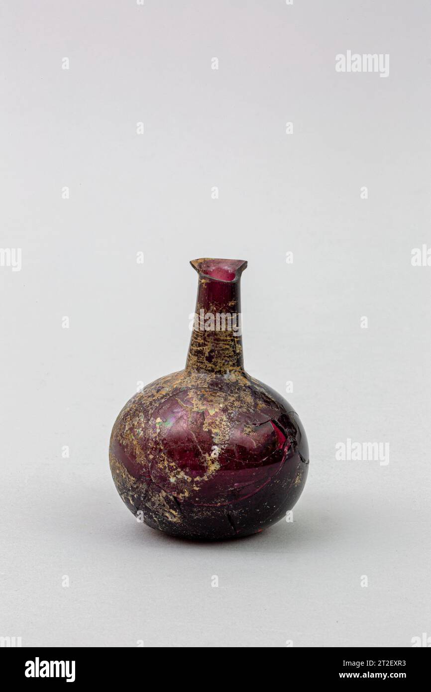 Glasparfümflasche Roman 1. Jahrhundert CE durchscheinend tiefviolett.umgestürzt mit Lippe in der Flamme gerundet; zylindrischer Hals, nach unten ausdehnend; Hocke, kugelförmiger Körper; leicht konkaver Boden. gebrochen und repariert, zwei Drittel des Rands fehlen und zwei große Löcher im Körper; einige Nadelstiche und größere Blasen; Flecken von stumpfem, cremebraunem Wetter und schillerndem Aussehen. Mehr anzeigen. Parfümflasche aus Glas. Roman. Jahrhundert n. Chr. Glas; geblasen. Frühe Kaiserzeit. Glas Stockfoto