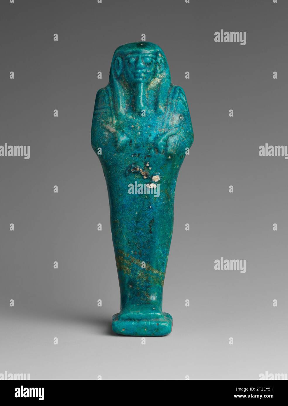 Schabti von Djedhor Spätzeit–Ptolemäer Periode ca. 360–300 v. Chr. diese kleine Grabfigur (Shabti) stammt aus dem Grab einer wohlhabenden Familie. Der Patriarch, der Priester Djedhor, wurde mit seiner Frau Nebtaihet und zwei anderen Personen in einer Kammer bestattet, mit ihren drei Söhnen in der zweiten. Am Kopf des Steinsarkophags von Djedhor befanden sich zwei Schabti-Kästen, eine mit 198 Figuren und die zweite mit 196. Diese Schabtis waren von zwei verschiedenen Größen (die größeren wie hier und die kleineren, siehe 02.4,151). Sie sind alle mumiform, mit hinteren Säulen und Sockeln. Jeder trägt eine Kurve Stockfoto