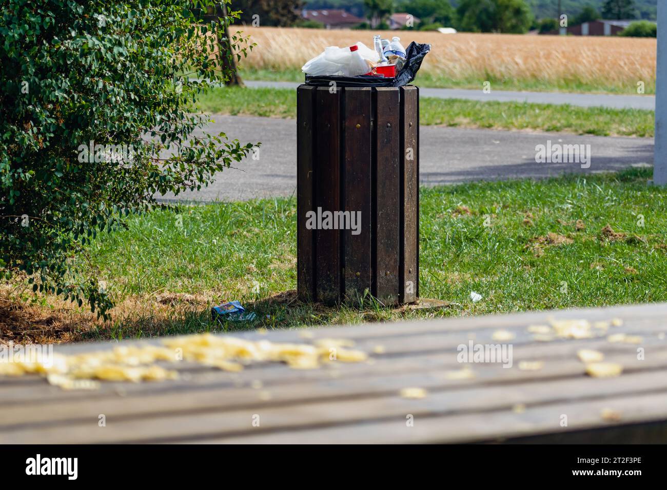 Öffentliche Mülltonne in einem Park voller überlaufender Müll Stockfoto