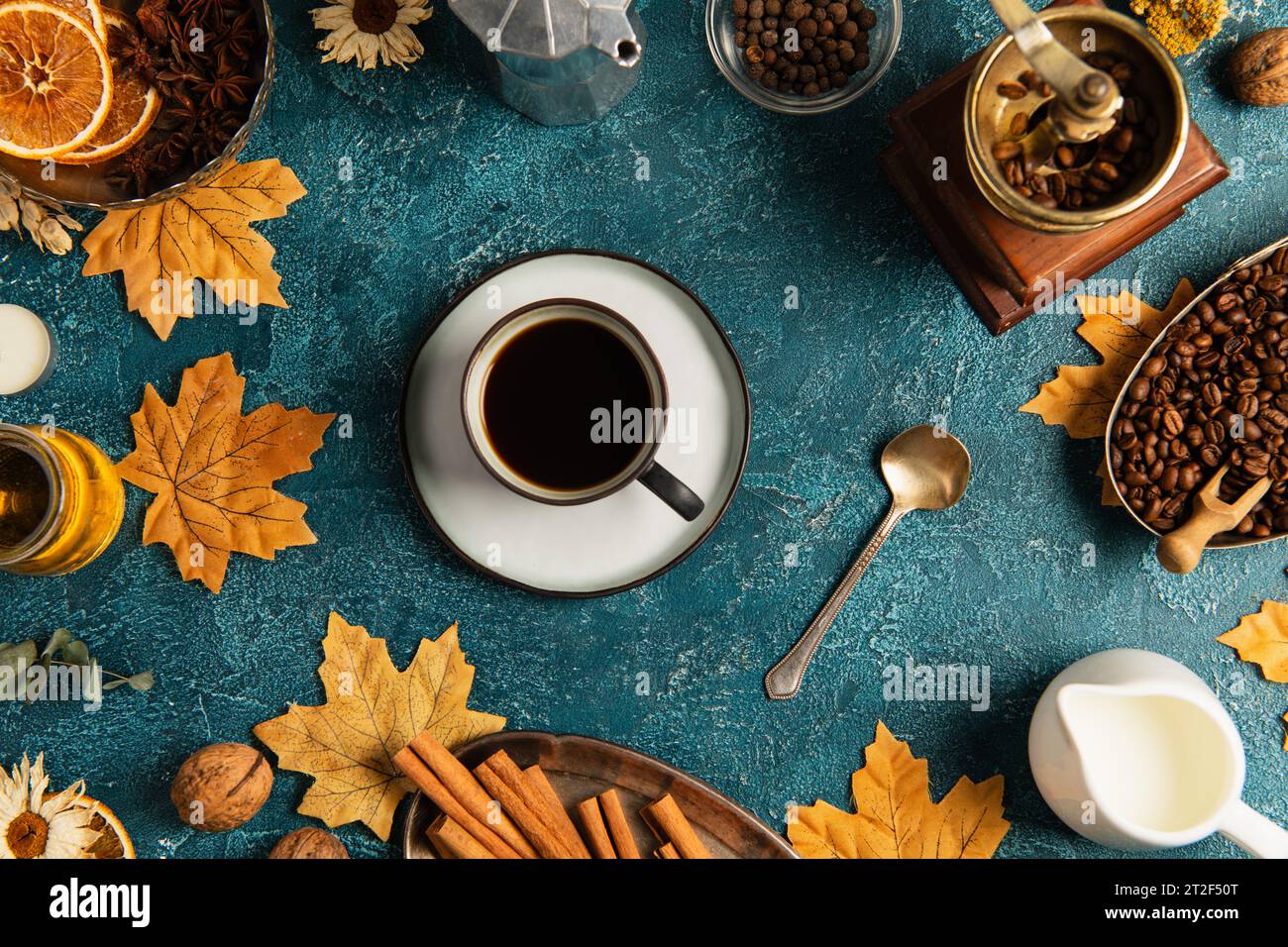 Stillleben an thanksgiving, Kaffeetasse auf blau strukturierter Tischplatte mit Ahornblättern und Herbstdekor Stockfoto