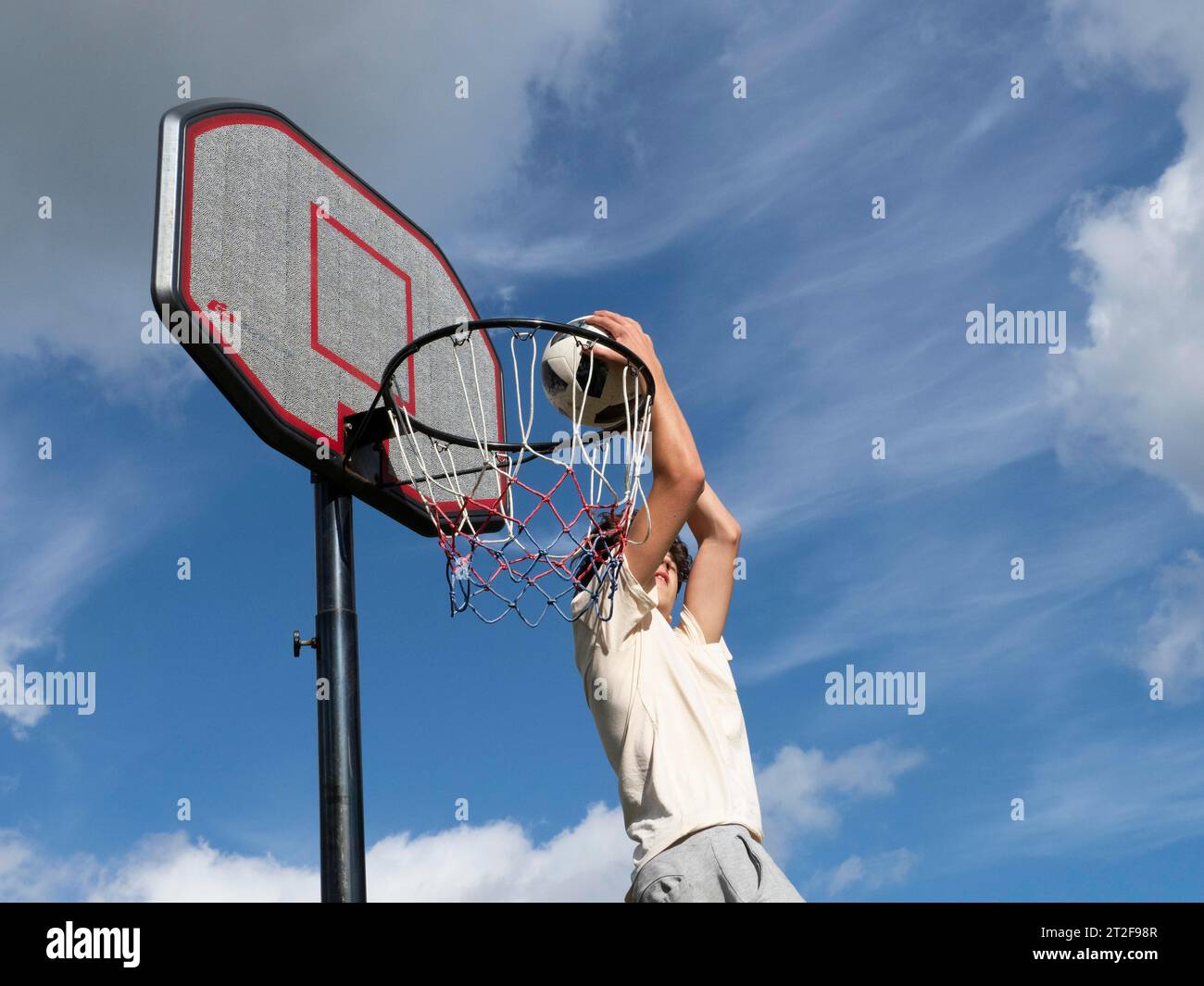 Basketball Sprung mit dem Ball in den Korb und ins Netz, Junge 14 Jahre, Sportaktivität mit Kindern, Deutschland Stockfoto