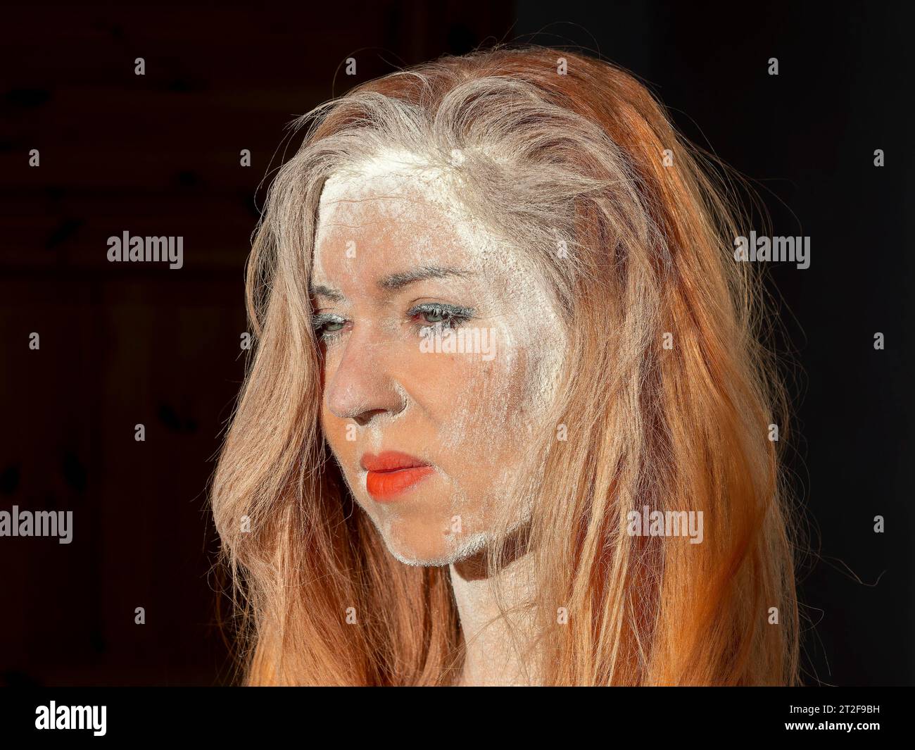 Frau mit roten Lippen, langen Haaren, staubigem Gesicht, Drama, Verzweiflung, Leiden und Krieg Stockfoto