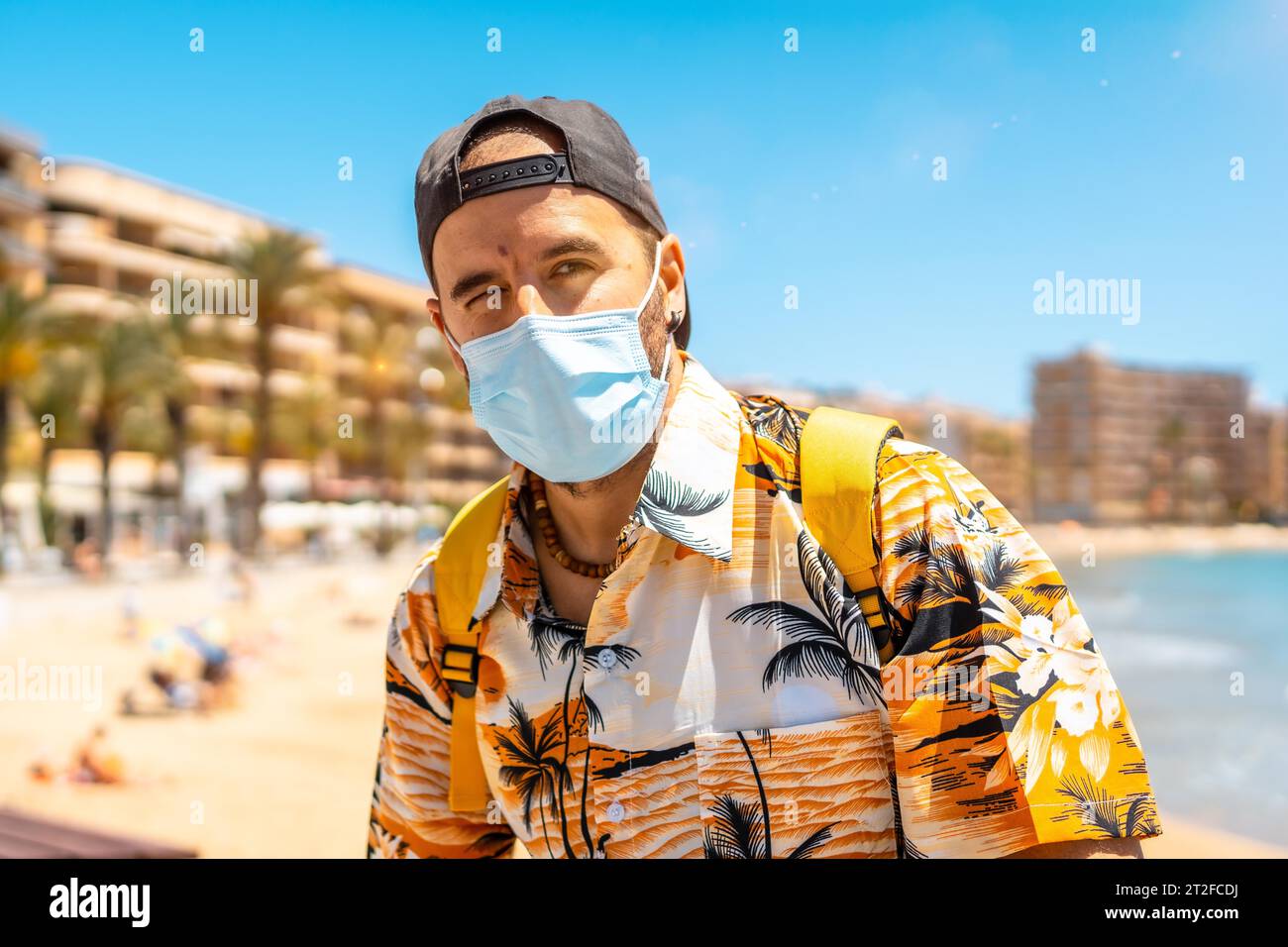 Ein junger Mann mit einer touristischen chirurgischen Maske am Strand von Cura in der Küstenstadt Torrevieja, Alicante, valencianische Gemeinschaft. Spanien, Mittelmeer Stockfoto