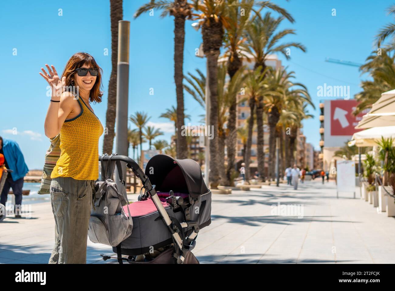 Eine junge Mutter, die ihr Baby im Auto in der Küstenstadt Torrevieja, Alicante, Valencia, herumläuft. Spanien, Mittelmeer Stockfoto