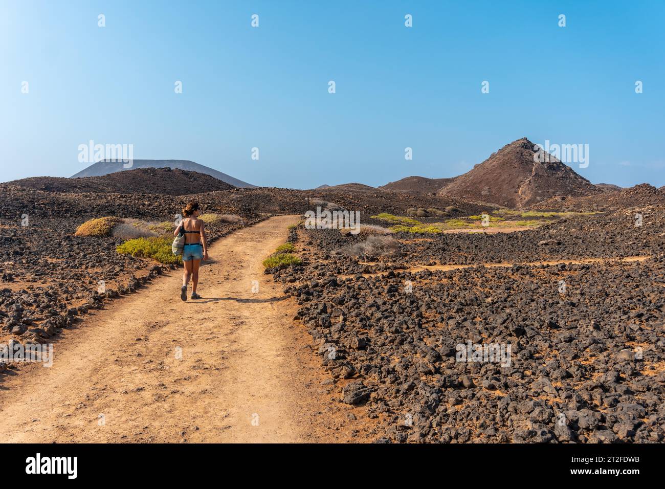 Eine junge Frau auf dem Weg nördlich der Isla de Lobos, entlang der Nordküste der Insel Fuerteventura, Kanarische Inseln. Spanien Stockfoto