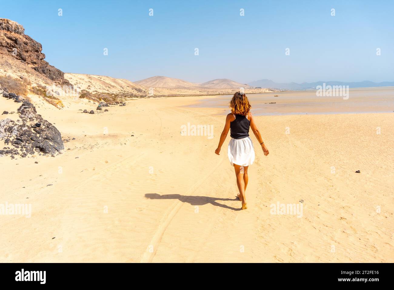 Ein junger Tourist, der am Strand von Sotavento spaziert, ideal für Sportarten wie Kitesurfen oder Sky Surfen im Süden von Fuerteventura, Kanarischen Inseln. Stockfoto