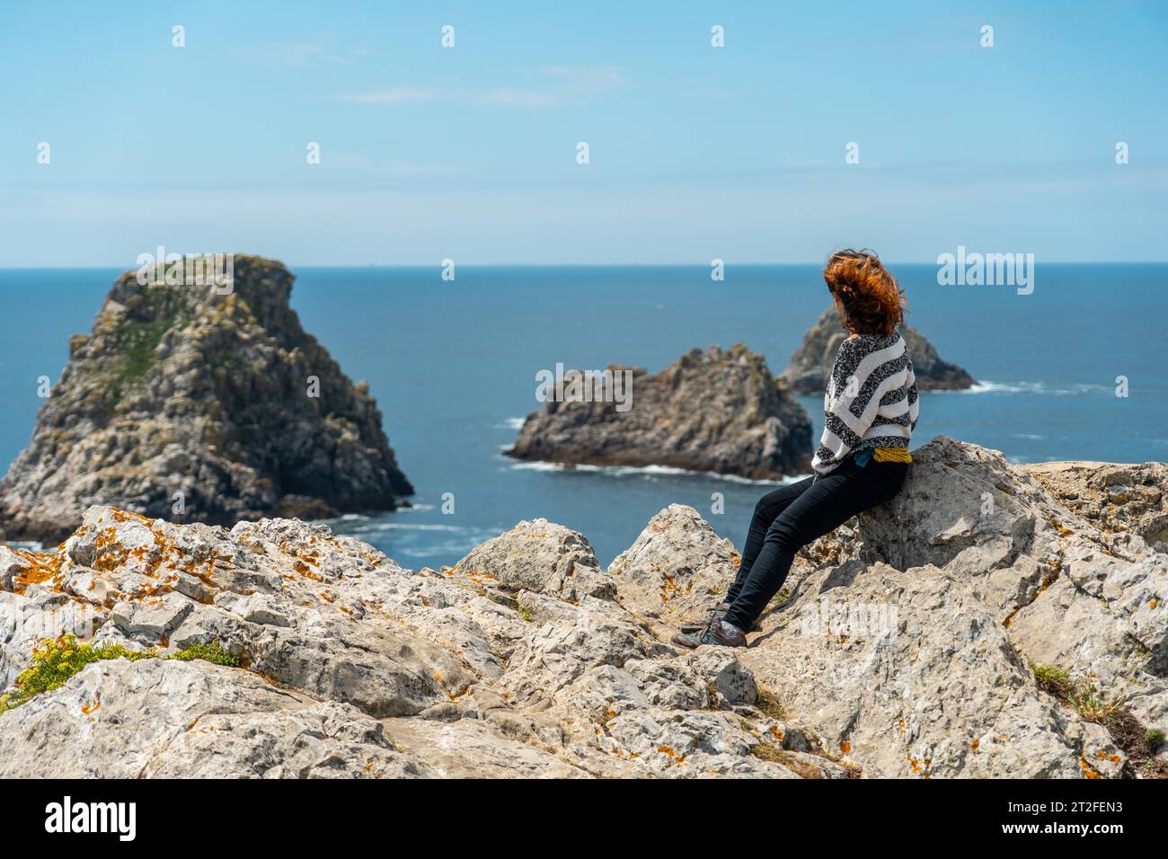 Ein junges Touristenmädchen, das das Meer am Pen Hir Point auf der Halbinsel Crozon in der französischen Bretagne, den drei berühmten Inseln in Frankreich, betrachtet Stockfoto