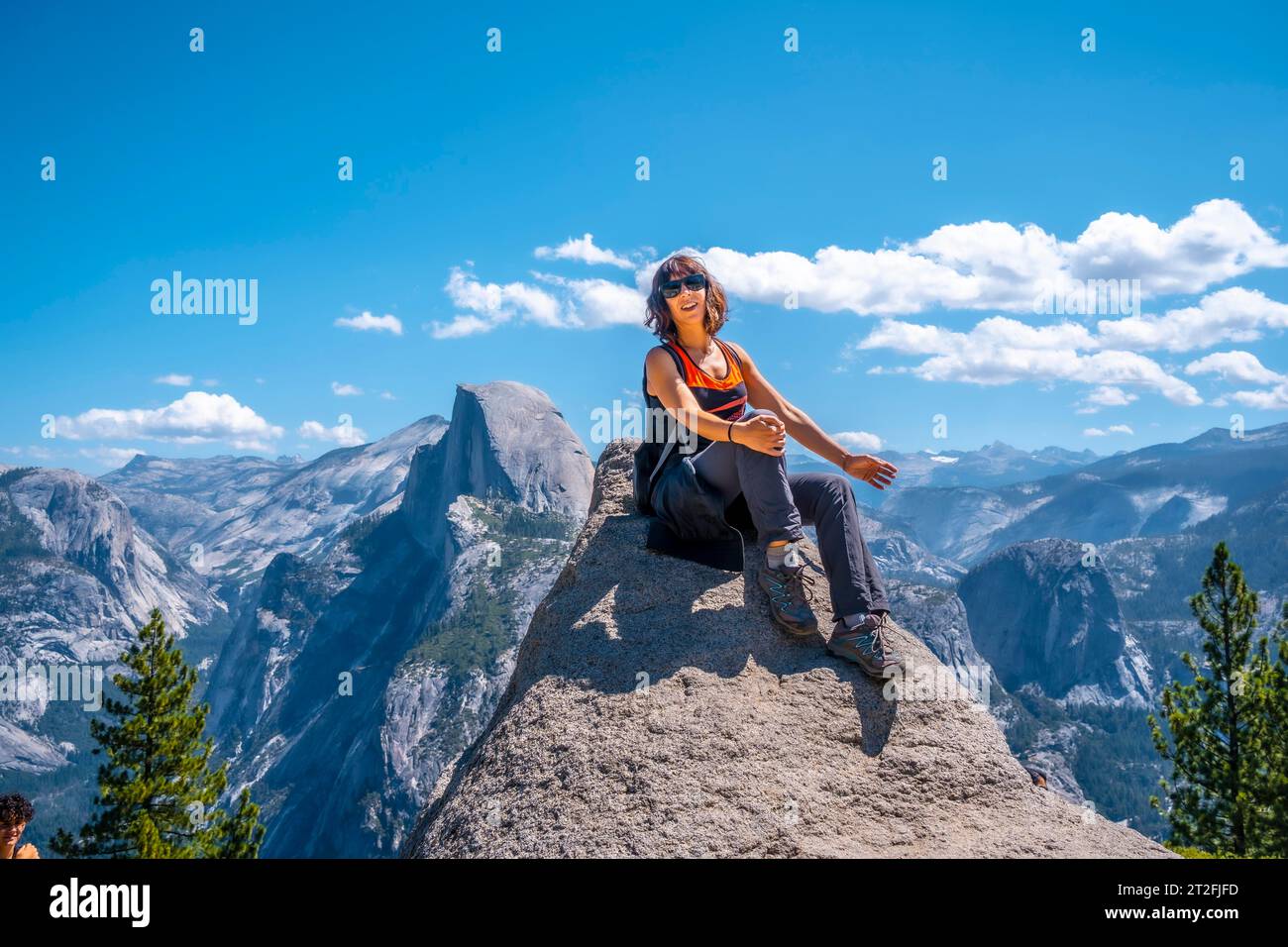Eine junge Frau in Rosa und Schwarz am Gletscherpunkt an der Half Dome Wand. Yosemite National Park, Usa Stockfoto