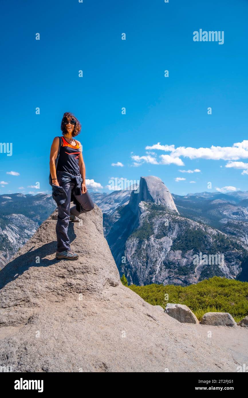 Eine junge Frau in Rosa und Schwarz am Gletscherpunkt an der Half Dome Wand. Yosemite National Park, Usa Stockfoto