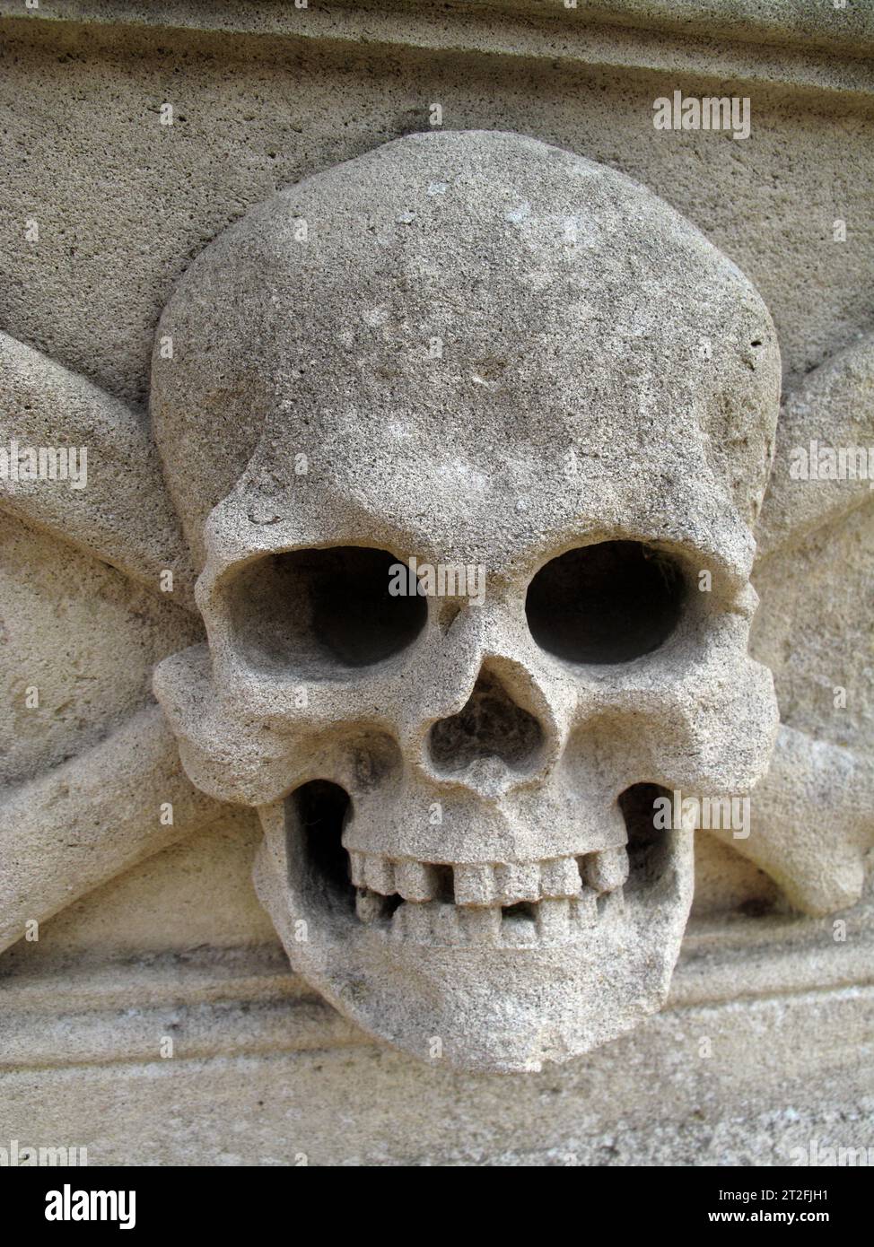 Sandsteinschnitzerei eines Schädels und Kreuzknochens an der Seite eines Kirchensarkophags Stockfoto