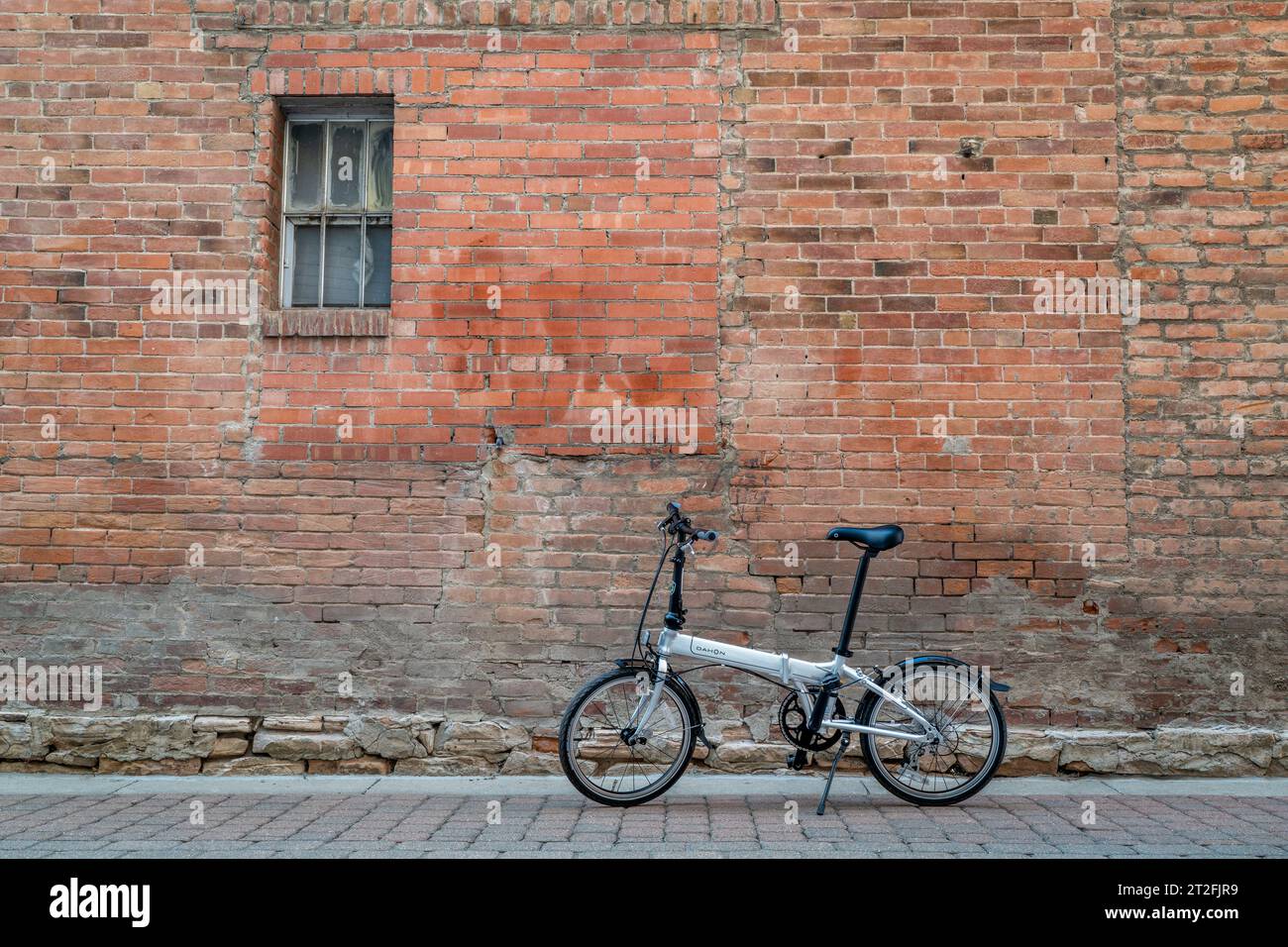 Fort Collins, CO, USA – 7. Mai 2023: Dahon Mariner D8, ein beliebtes, leichtes, faltbares Fahrrad in einer Gasse vor einer Mauer. Stockfoto