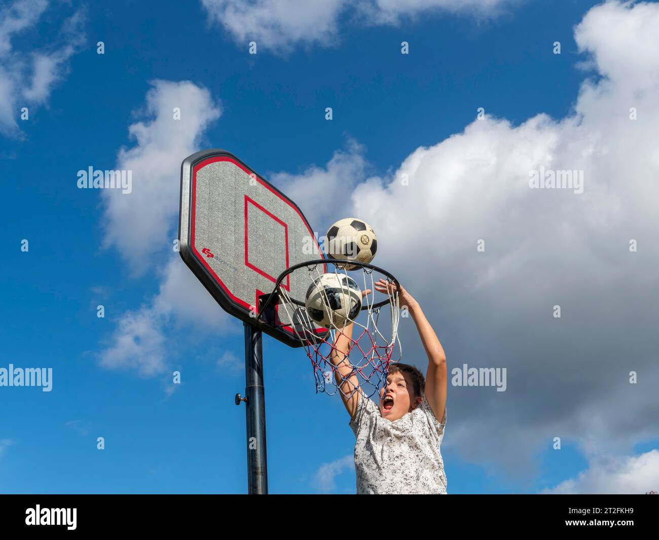 Basketball Sprung mit dem Ball in den Korb und ins Netz, Junge 13 Jahre, Sportaktivität mit Kindern, Deutschland Stockfoto