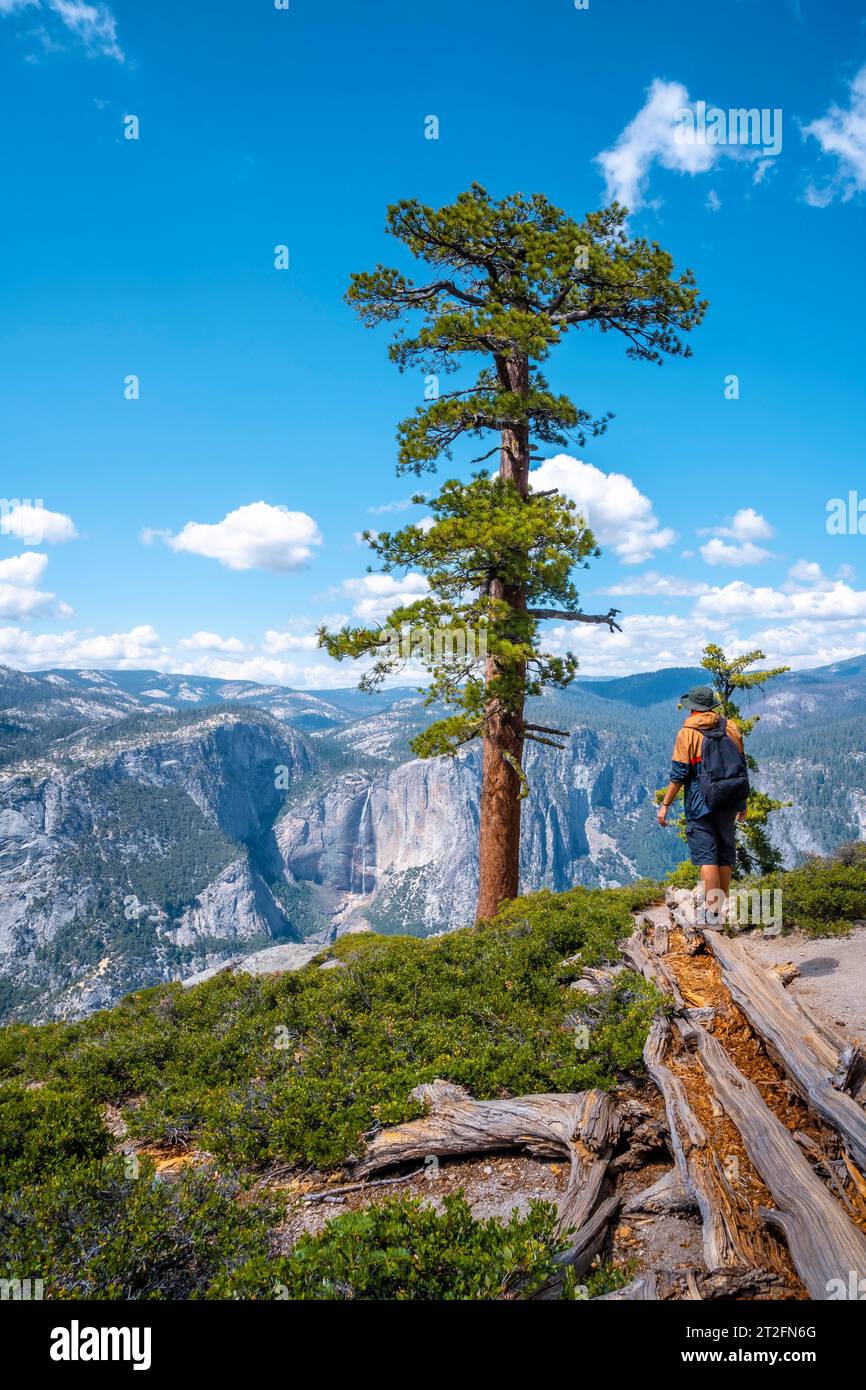 Ein junger Mann mit brauner Jacke im Sentinel Dome, der auf den Upper Yosemite Fall im Yosemite National Park blickt. Usa Stockfoto