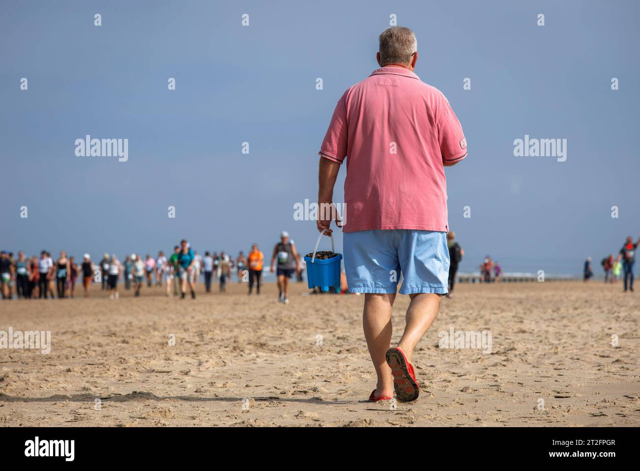 Mann mit Eimer am Strand in Oostkapelle auf der Halbinsel Walcheren, Zeeland, Niederlande. Mann mit Eimer am Strand von Oostkapelle auf Walcheren, Stockfoto