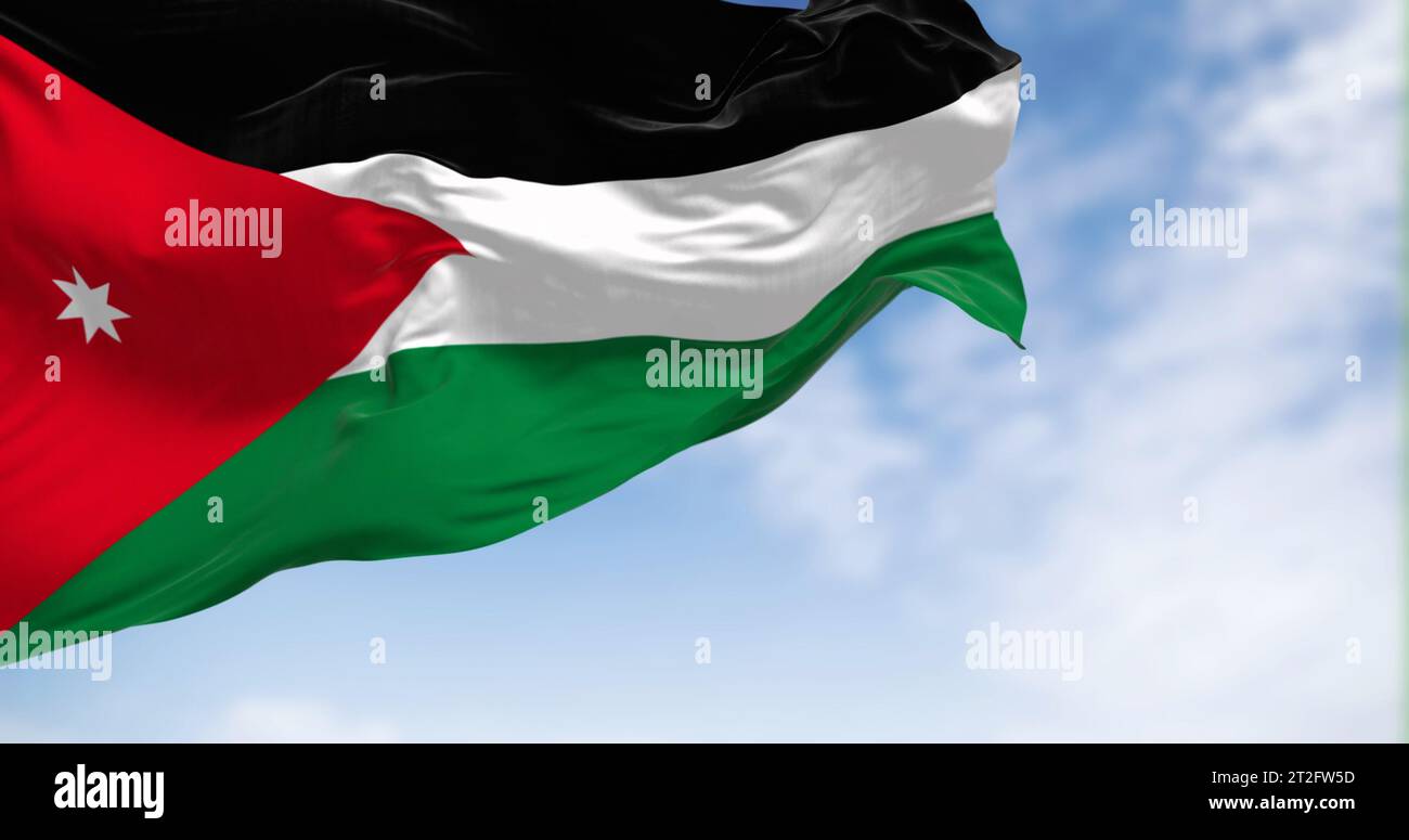 Die Nationalflagge Jordaniens winkt an einem klaren Tag im Wind. Schwarze, weiße und grüne horizontale Streifen mit einem roten Chevron auf der linken Seite mit einem weißen s Stockfoto