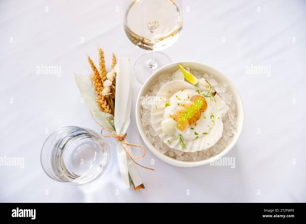 Jakobsmuschel in Soße mit fliegenden Fischkaviar auf einer Schale auf Eis in einem Restaurant. Hochwertige Fotos Stockfoto