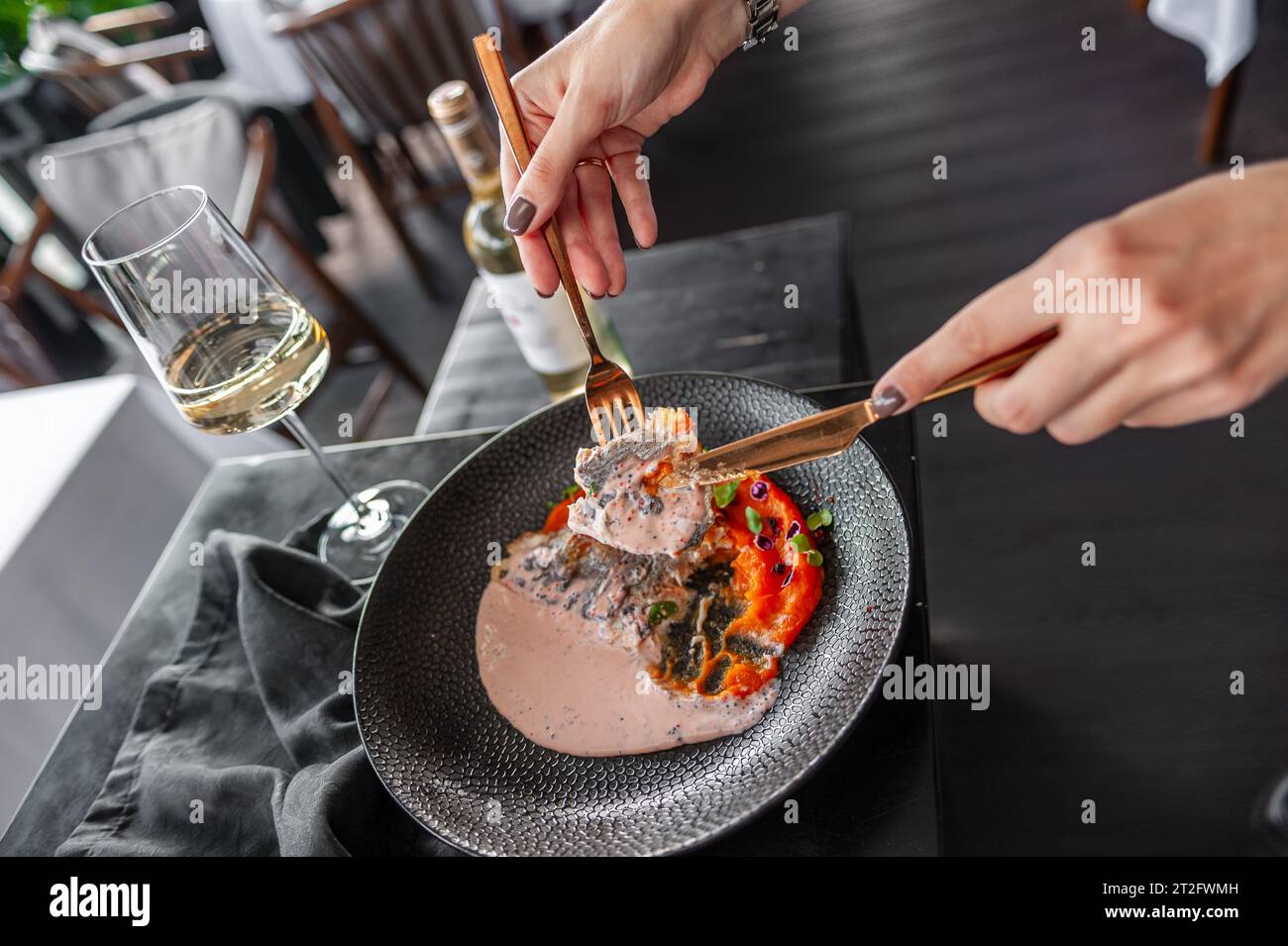 Wolfsbarsch oder dorado-Filet mit Süßkartoffelpüree und fliegenden Fischrogen-Sauce auf einem schwarzen Teller in einem Restaurant Stockfoto