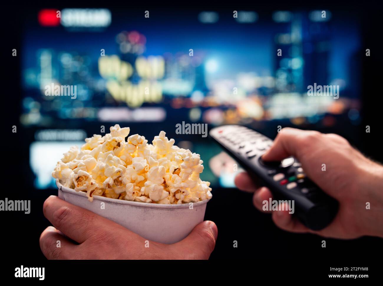 TV-Filmabend mit Familie. VOD-Plattform streamen. Popcorn und Fernbedienung. Videounterhaltung und Snack. Online-Film im Fernsehen abspielen. Stockfoto