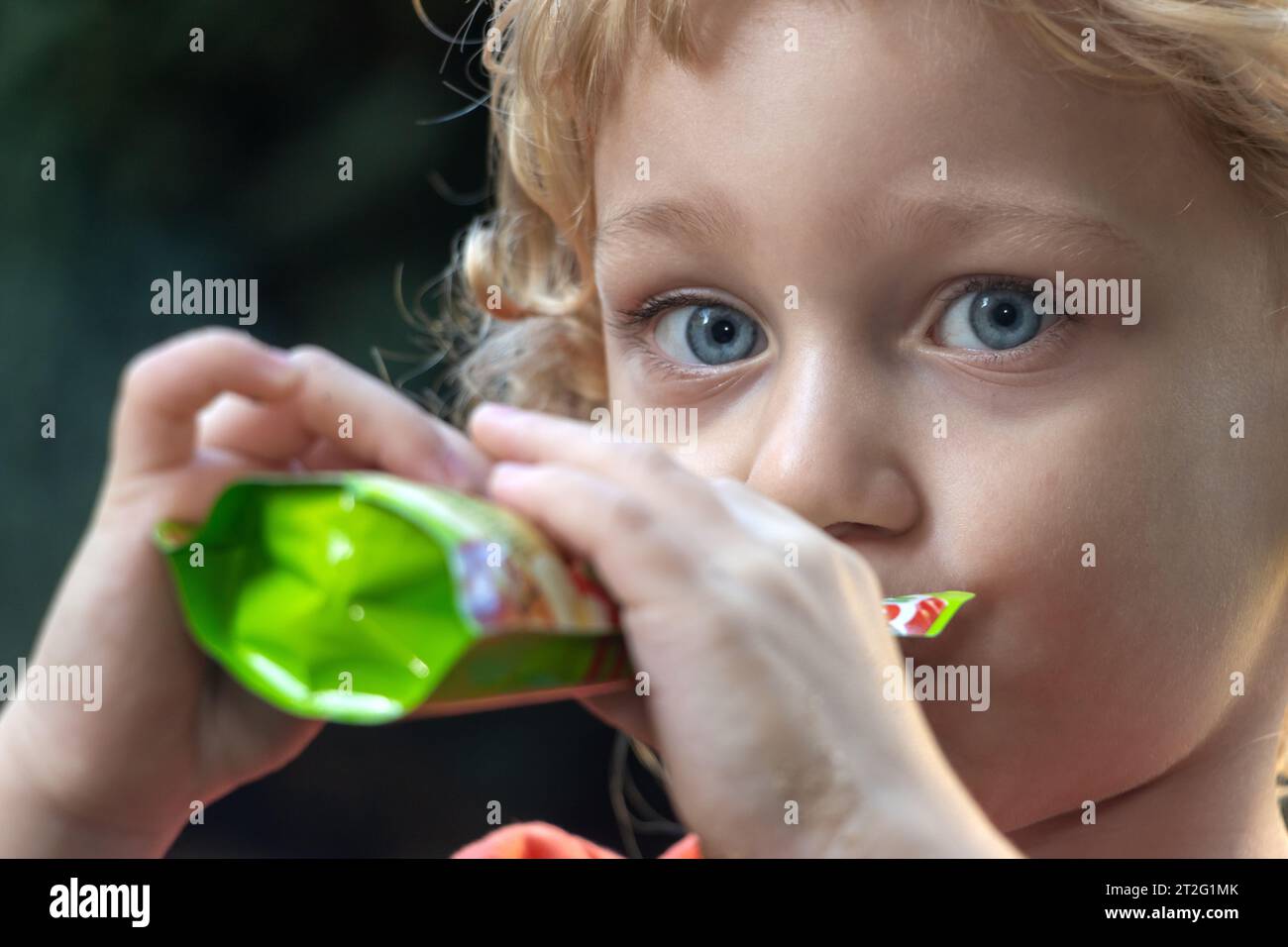 Porträt eines Jungen, der flüssiges Essen aus einem kleinen Beutel trinkt Stockfoto