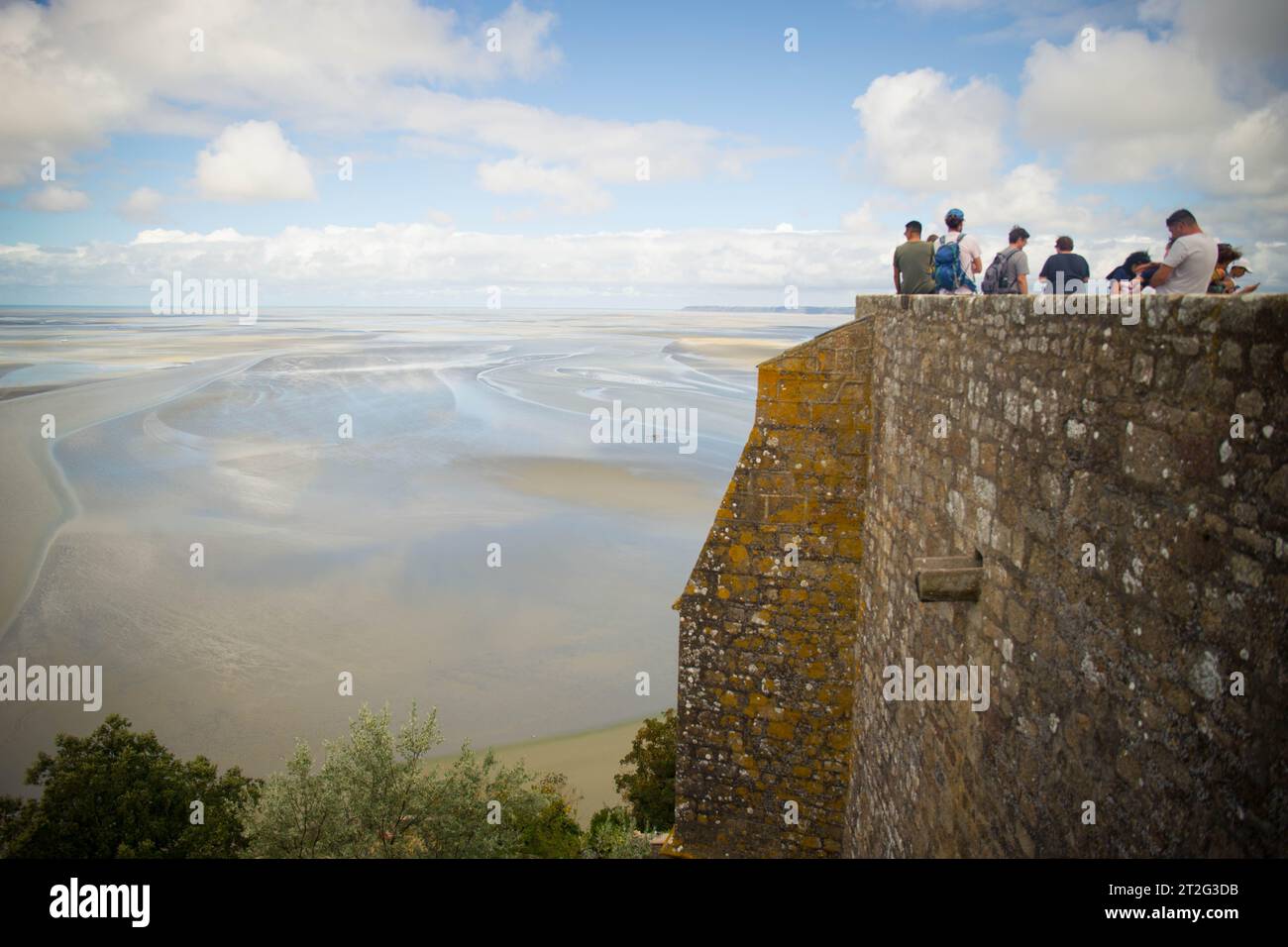 MONT SAINT MICHEL, AUGUST 2023 - Touristen bewundern an einem Sommertag die Aussicht auf die Bucht bei Ebbe von den Mauern der Abtei Mont Saint Michel. Stockfoto