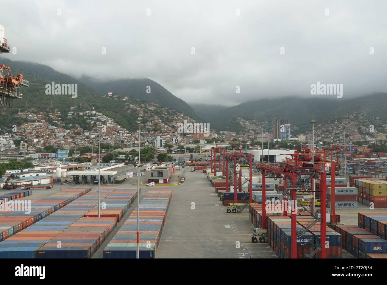 Containerterminal im Hafen von La Guaira, beobachtet von einem Frachtschiff, das unter Portalkranen verankert ist. Stockfoto