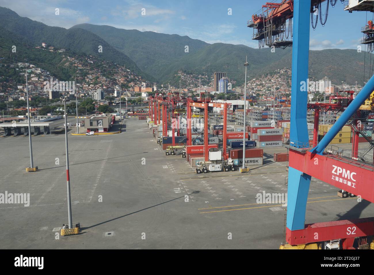 Modernes Containerterminal im Hafen von La Guaira, beobachtet von einem Frachtschiff, das unter Portalkranen vertäut ist. Stockfoto