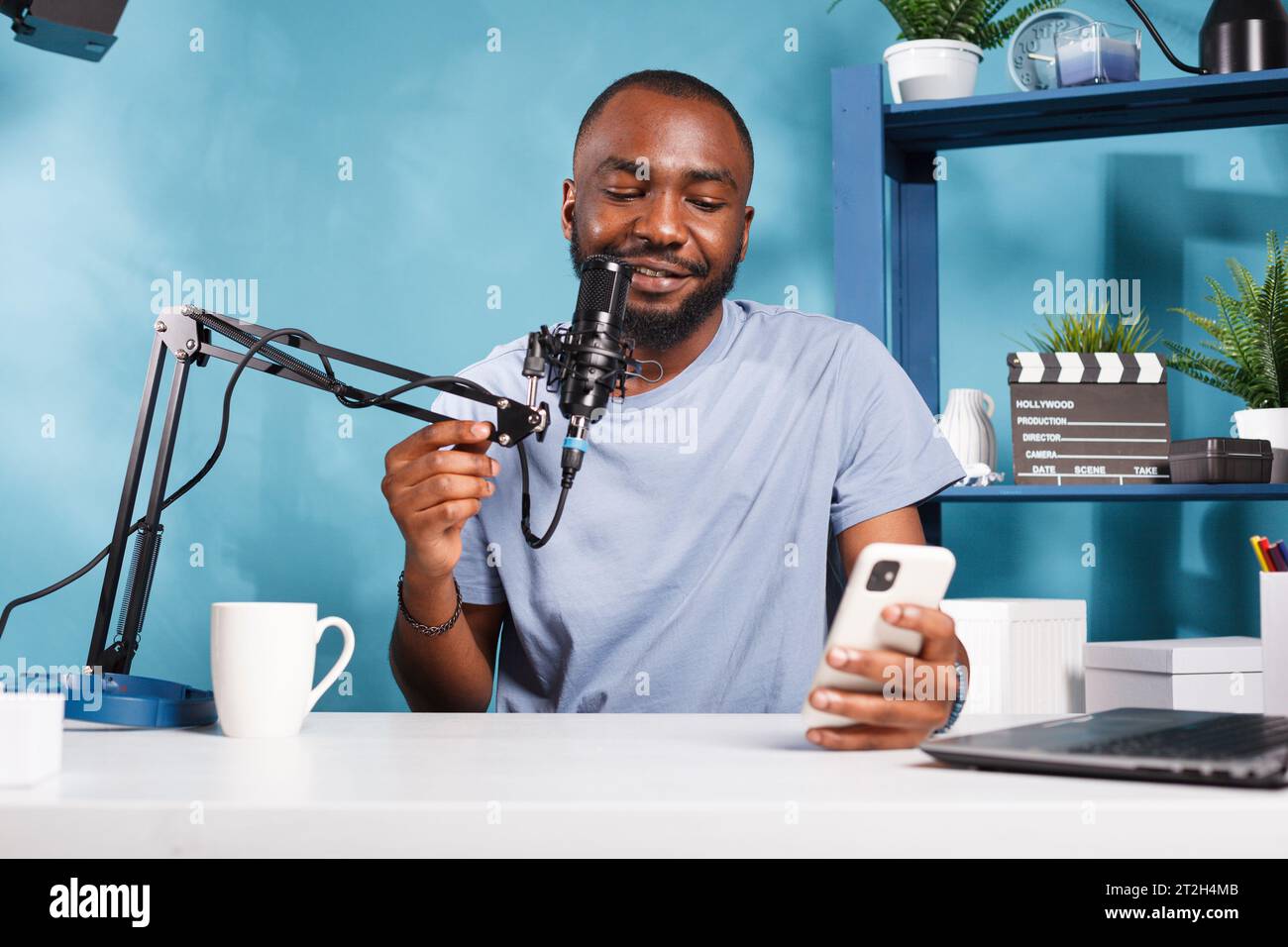 Fröhlicher Blogger, der beim Online-Streaming Erkenntnisse und Neuigkeiten vom Smartphone weitergibt. Lächelnder afroamerikanischer Vlogger, der digitale Inhalte erstellt und Fragen auf dem Mobiltelefon beantwortet Stockfoto